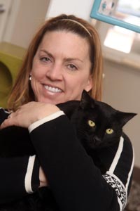 Woman holding an all-black cat at the shelter