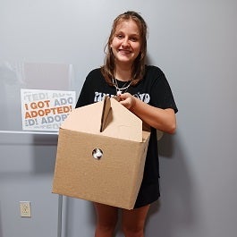 Woman holding cat carrier box with cat peeking out