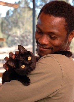 Man in tan shirt holding black cat
