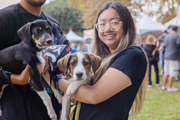 woman with glasses holding a brown and white puppy