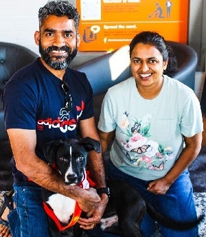 Man and woman holding black and white dog