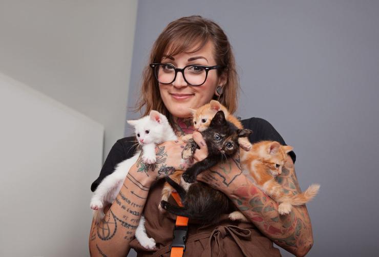 Smiling woman holding an armful of kittens