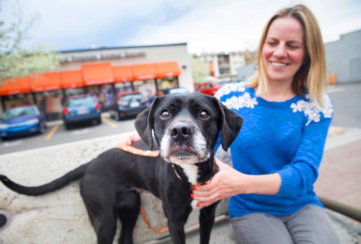 Smiling person sitting in front of Best Friends Pet Adoption Center in Salt Lake City with a dog