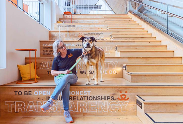 Person sitting on the steps with a dog at the Best Friends Pet Resource Center in Bentonville, Arkansas