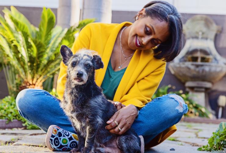 Smiling person sitting with a small dog outside