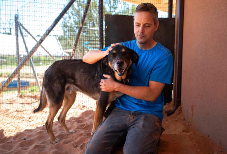 Person kneeling down next to a dog and petting the dog
