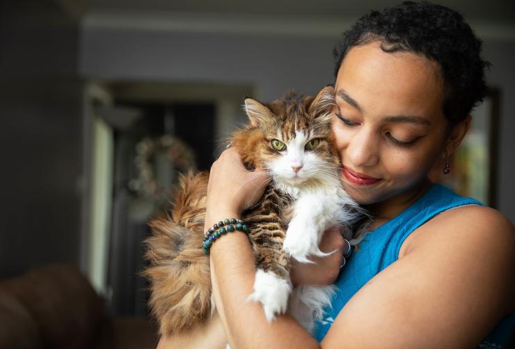 Person cradling a brown and white tabby cat in her arms