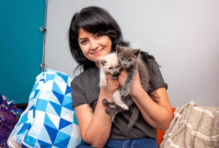 Smiling person holding two tiny kittens
