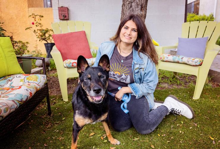 Smiling person relaxing in a yard with a happy dog