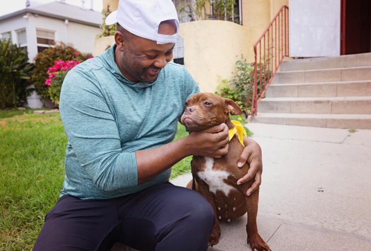 Smiling person sitting with a dog outside on some steps