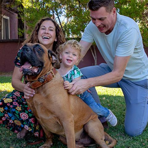 Smiling family hugging a big brown dog