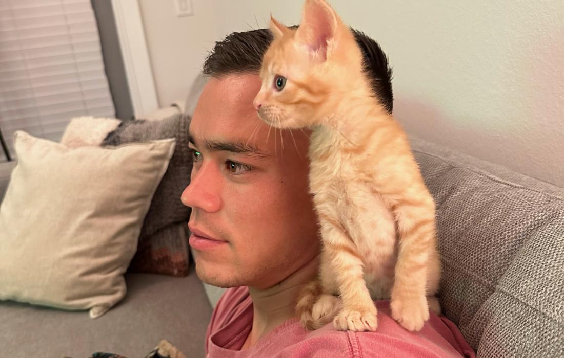 Sam Junqua with an orange kitten on his shoulder