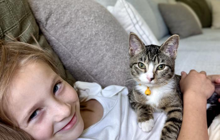 Clara lying on a couch with Sara the kitten on her chest