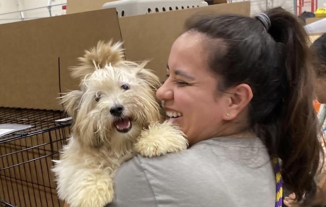 Smiling person holding a happy fluffy white dog