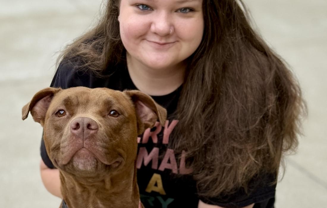 Ariel the dog sitting beside a smiling woman