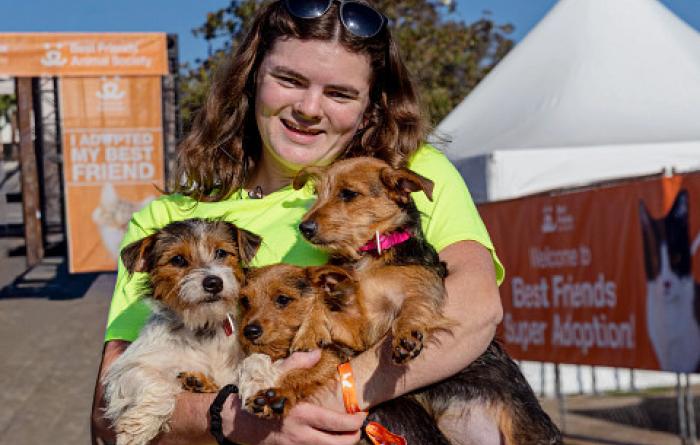 Person carrying three puppies at the Best Friends Super Adoption in Los Angeles