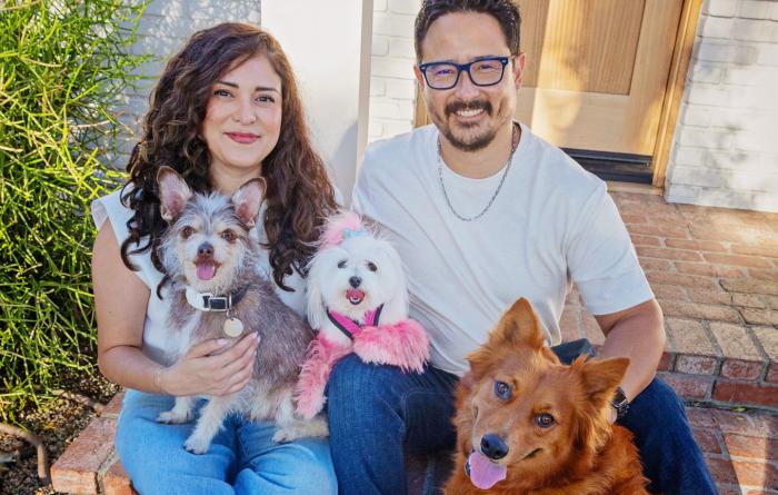 woman and man sitting on front steps with three dogs