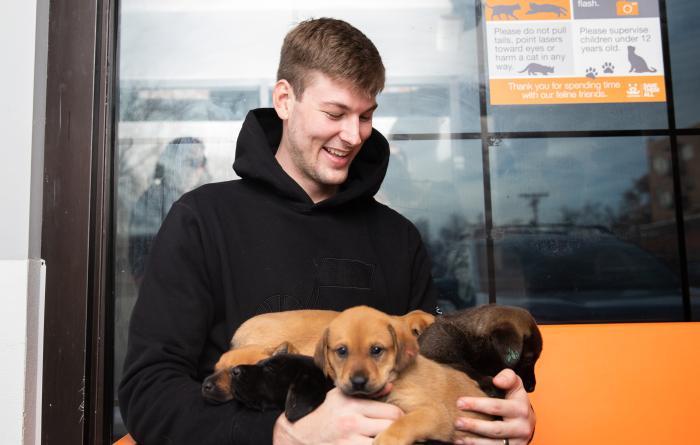 Kyle Filipowski holding multiple puppies on his lap
