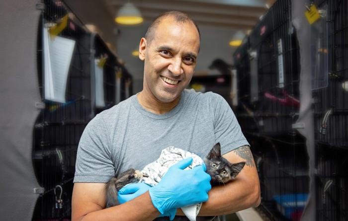 Volunteer Robert Lobo cradling a kitten in his arms