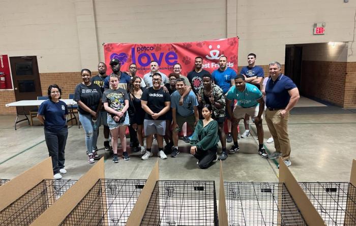 All the people from the adoption event with wire kennels in the foreground