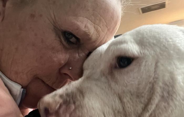 Missy Kidwell forehead to forehead with a large white dog