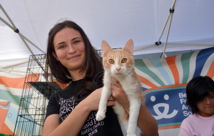 Smiling person holding a cat at a Best Friends pet adoption event