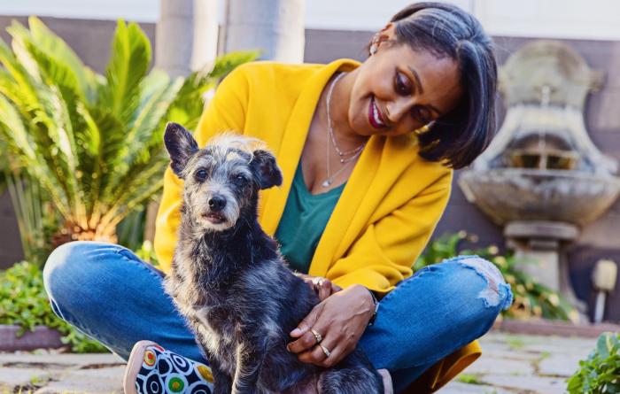 Smiling person sitting with a small dog outside