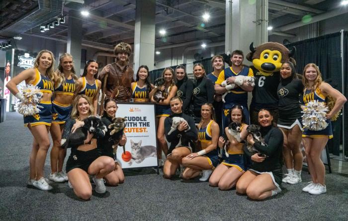 Cheerleaders holding puppies beside a Best Friends sign