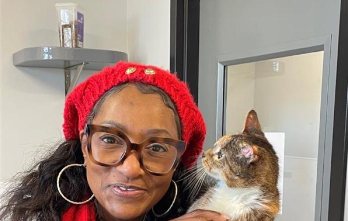 Person wearing red and holding a calico cat