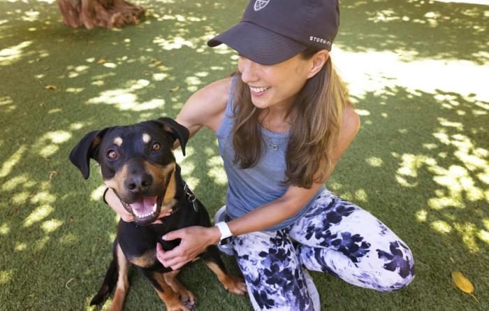 Smiling dog outside on some grass being held by a person wearing a hat