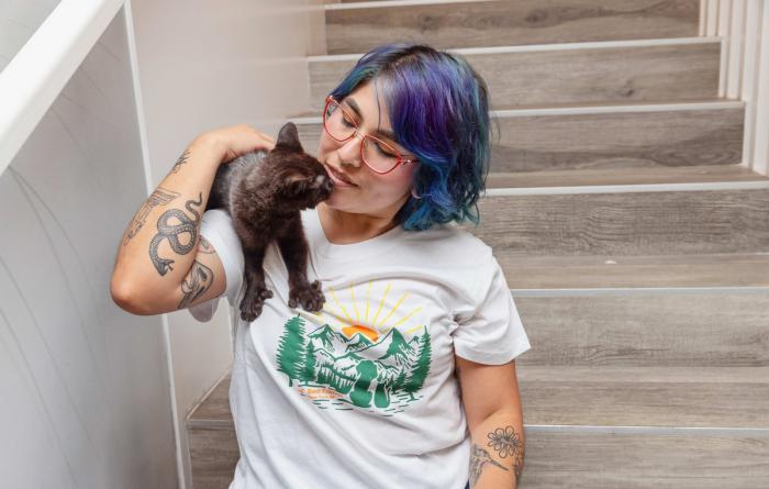 Person holding a black kitten on her shoulder