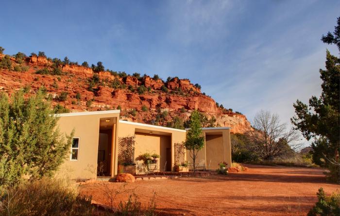 Small tan building with a backdrop of red rock cliffs and blue sky