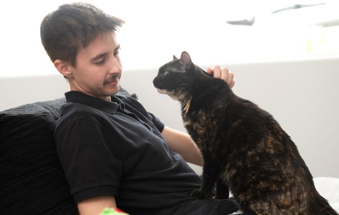 Profile of Emmalee the cat sitting on Isaac's lap while he pets her
