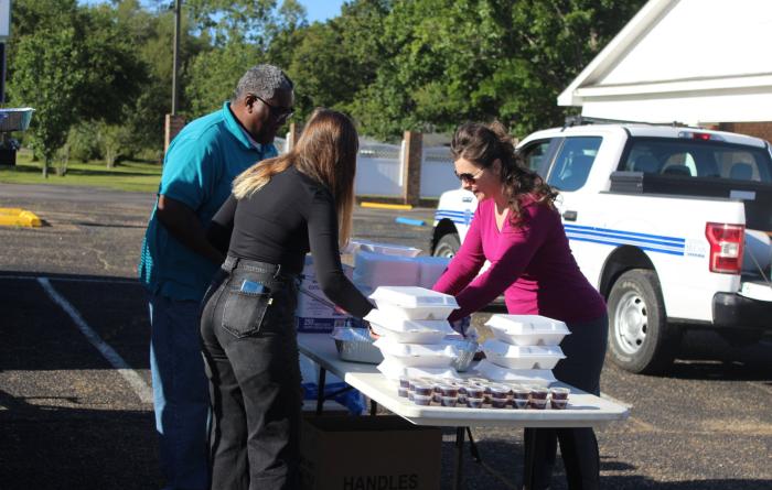 People next to a table full of styrofoam containers containing food from the Pancakes and Puppies fundraiser