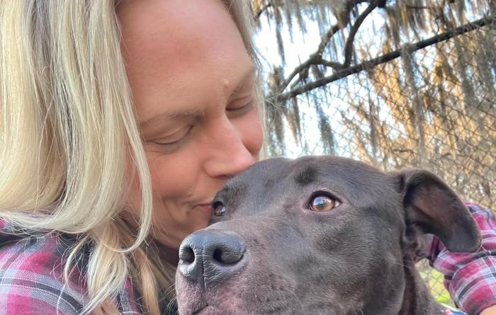 Person kissing the head of Delilah the dog