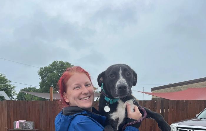 Smiling person holding a dog rescued from a flood