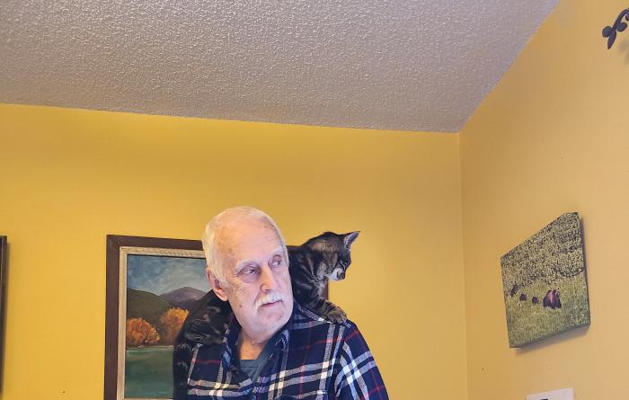 Eeyore the cat lying on Allen Burkhart's shoulder