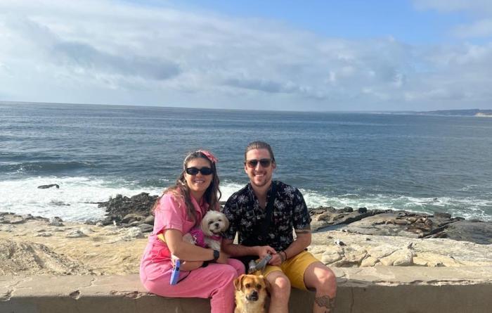 Bagel the dog on a beach with his two people and another dog