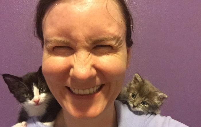 Lizel Allen laughing with a kitten on each of her shoulders