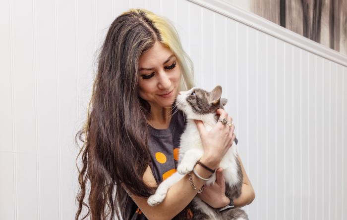 Smiling person holding a cat in her arms