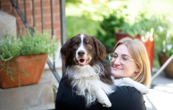 Smiling person outside with a brown and white dog whose paws are over her shoulder