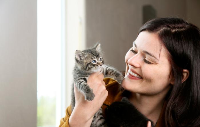 Smiling person holding a tabby kitten