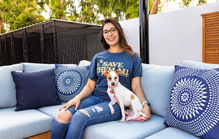 Smiling person wearing a "Save Them All" t-shirt while sitting with a dog outdoors with a small dog