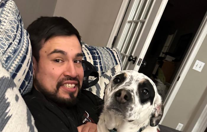 Neo the dog snuggling with a smiling person on a couch