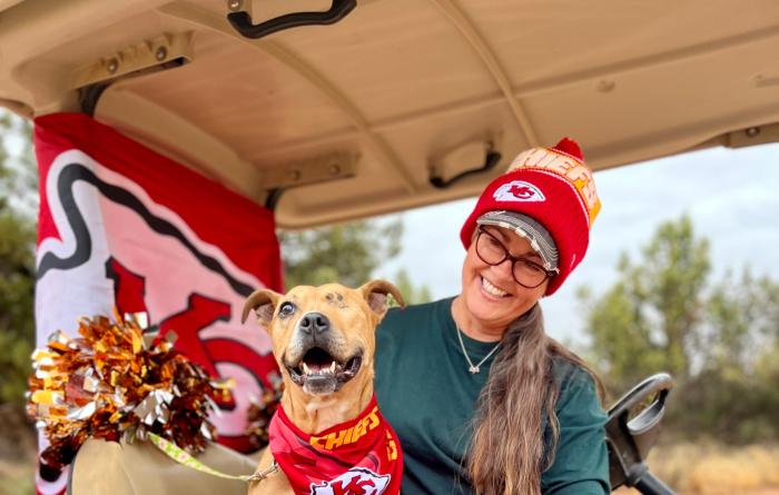 Norberta the dog wearing a Kansas City Chiefs bandanna behind a sign