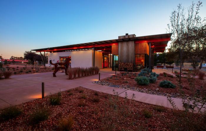 Exterior photo of the sun setting behind a modern building in the desert