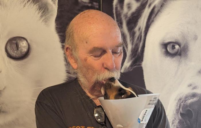 Volunteer Steve Pack holding a puppy wearing a protective cone