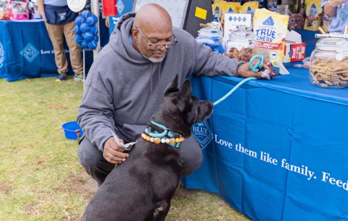 Person and leashed dog at the Blue Buffalo vendor table at the Los Angles Super Adoption