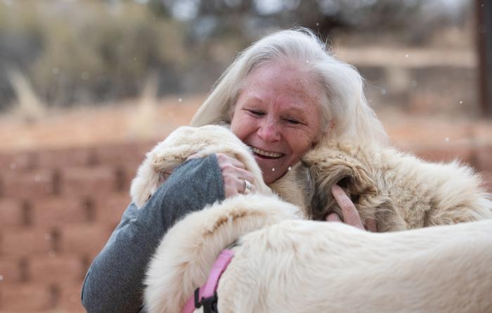 Val Hardin smiling and hugging Anna and Racer the dogs