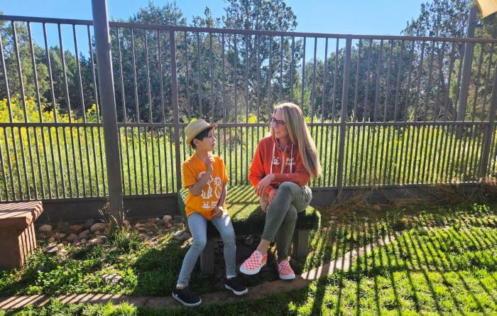 Julian Lin sitting on a bench inside a fence with Best Friends CEO Julie Castle